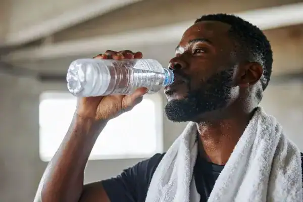 Image of man drinking water to improve hydration Herne after work out.